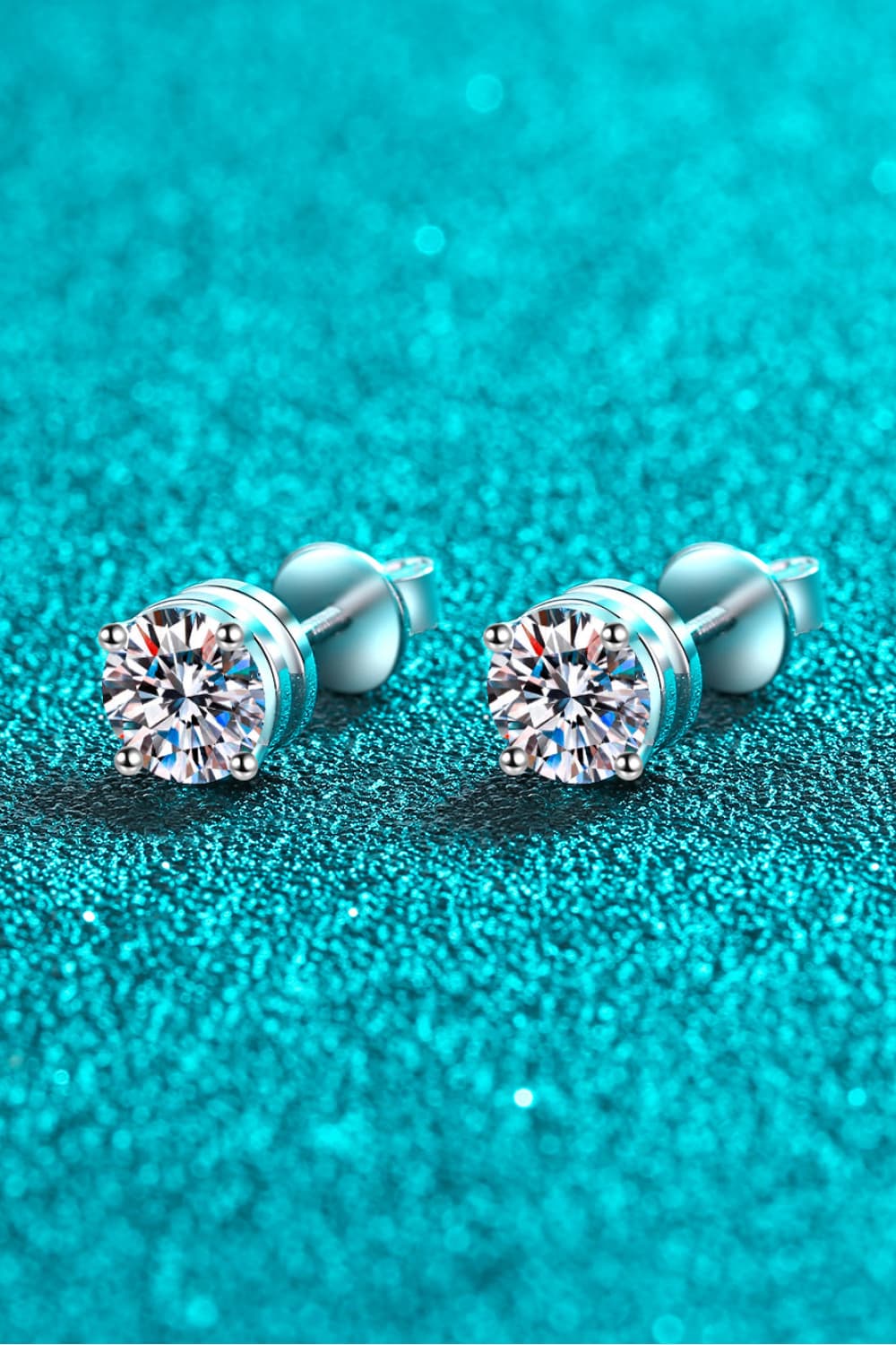 "Minimalist Moissanite stud earrings made with 925 sterling silver, rhodium-plated, featuring 1 carat Moissanite stones in each earring for a total of 2 carats. Includes a certificate of stone properties and comes with a matching box."