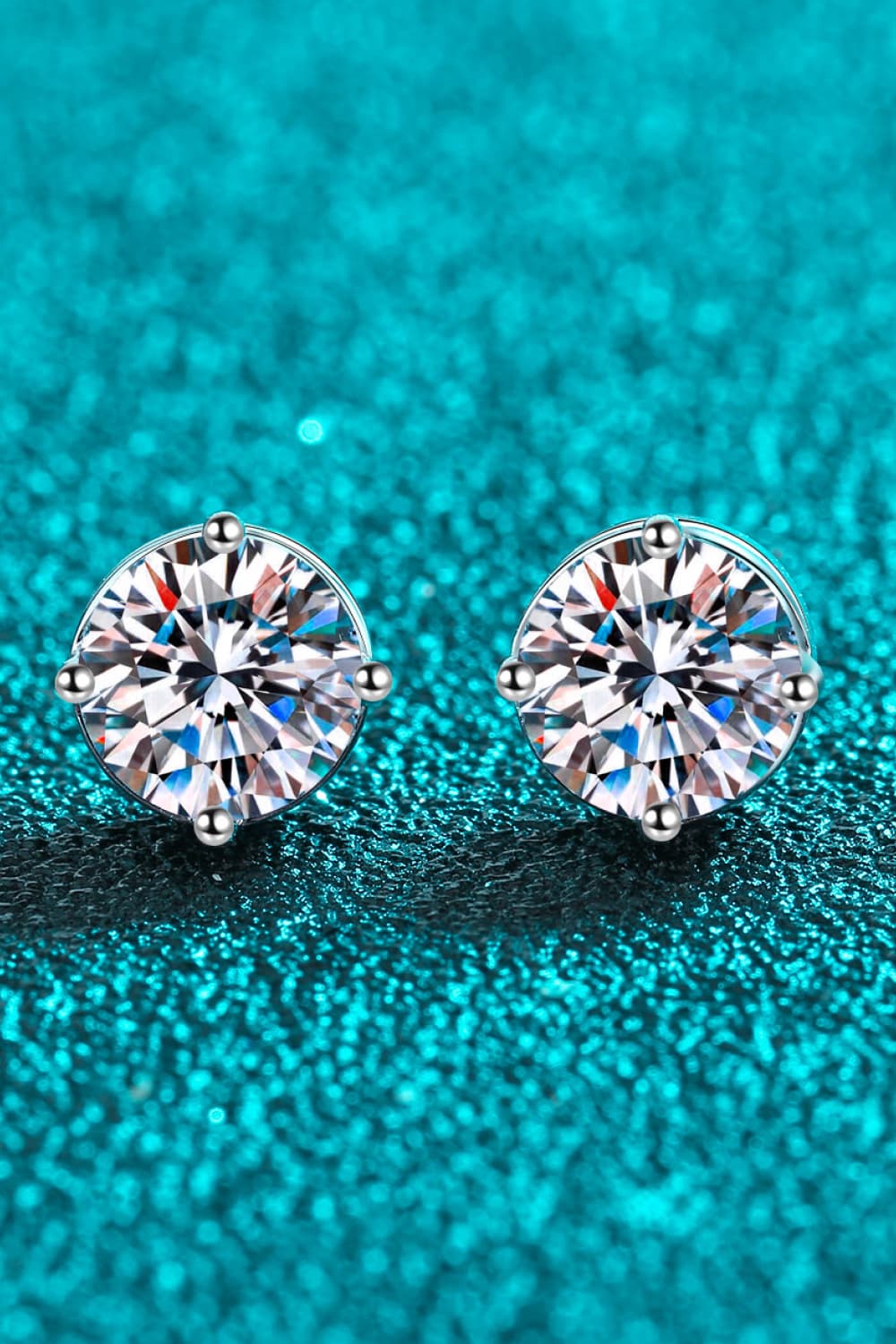 "Minimalist Moissanite stud earrings made with 925 sterling silver, rhodium-plated, featuring 1 carat Moissanite stones in each earring for a total of 2 carats. Includes a certificate of stone properties and comes with a matching box."